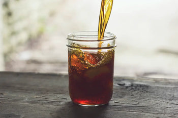 Iced tea being poured into a glass jar for refreshing summer beverage