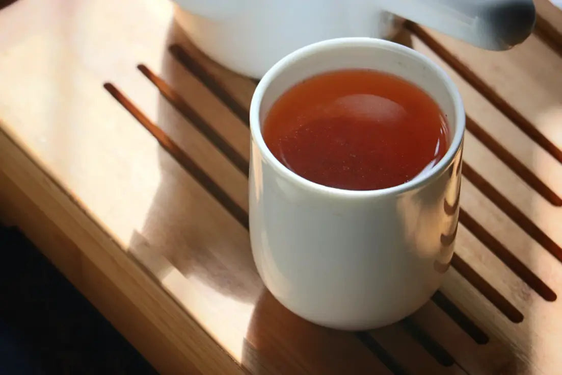 White teacup filled with tea for Tea Culture 101 article comparing Green Tea and Red Tea