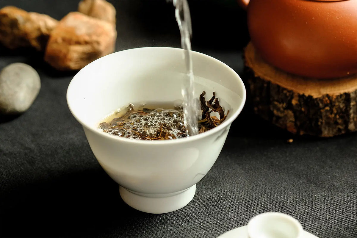 White teacup being filled with hot tea in a guide on brewing Pu’er tea