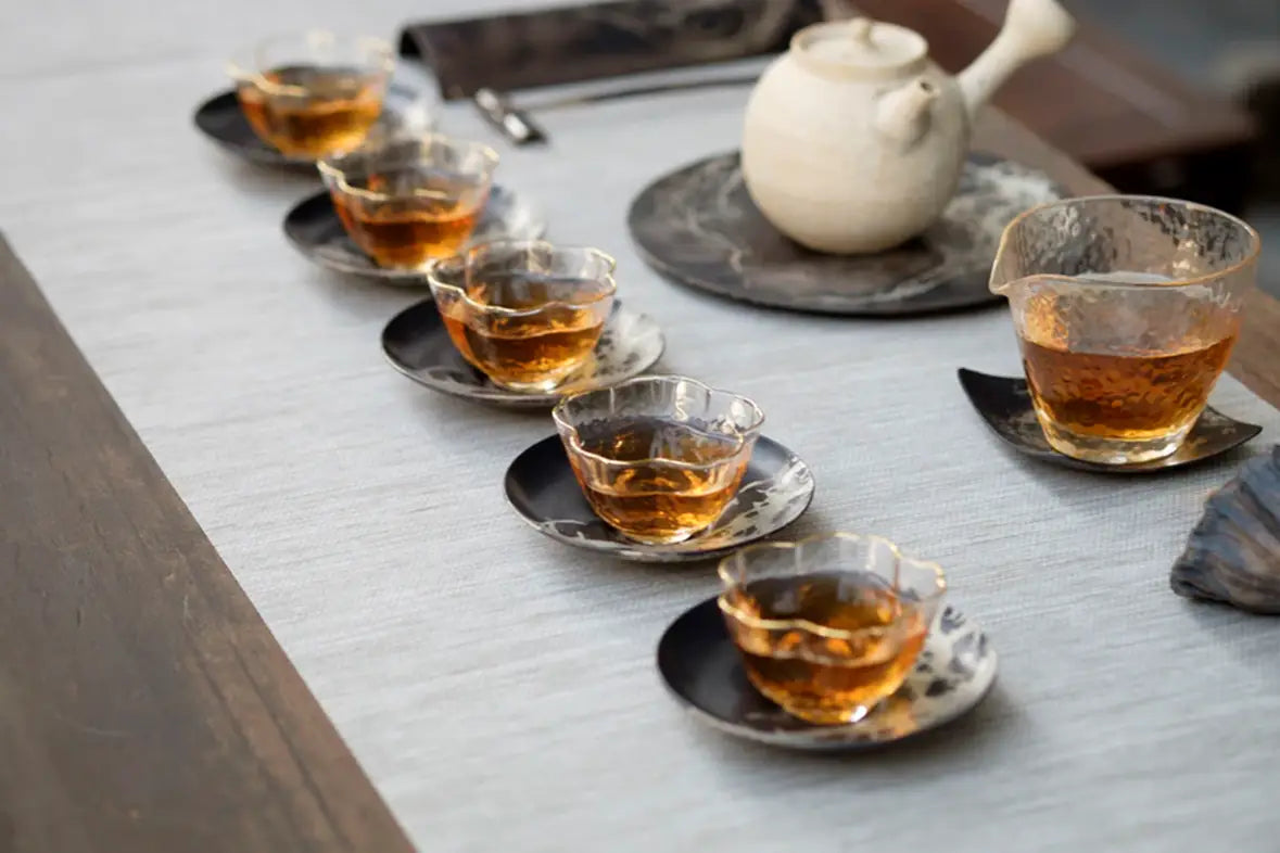 Tea set with clear cups on a table, related to Puerh Tea and dental health article