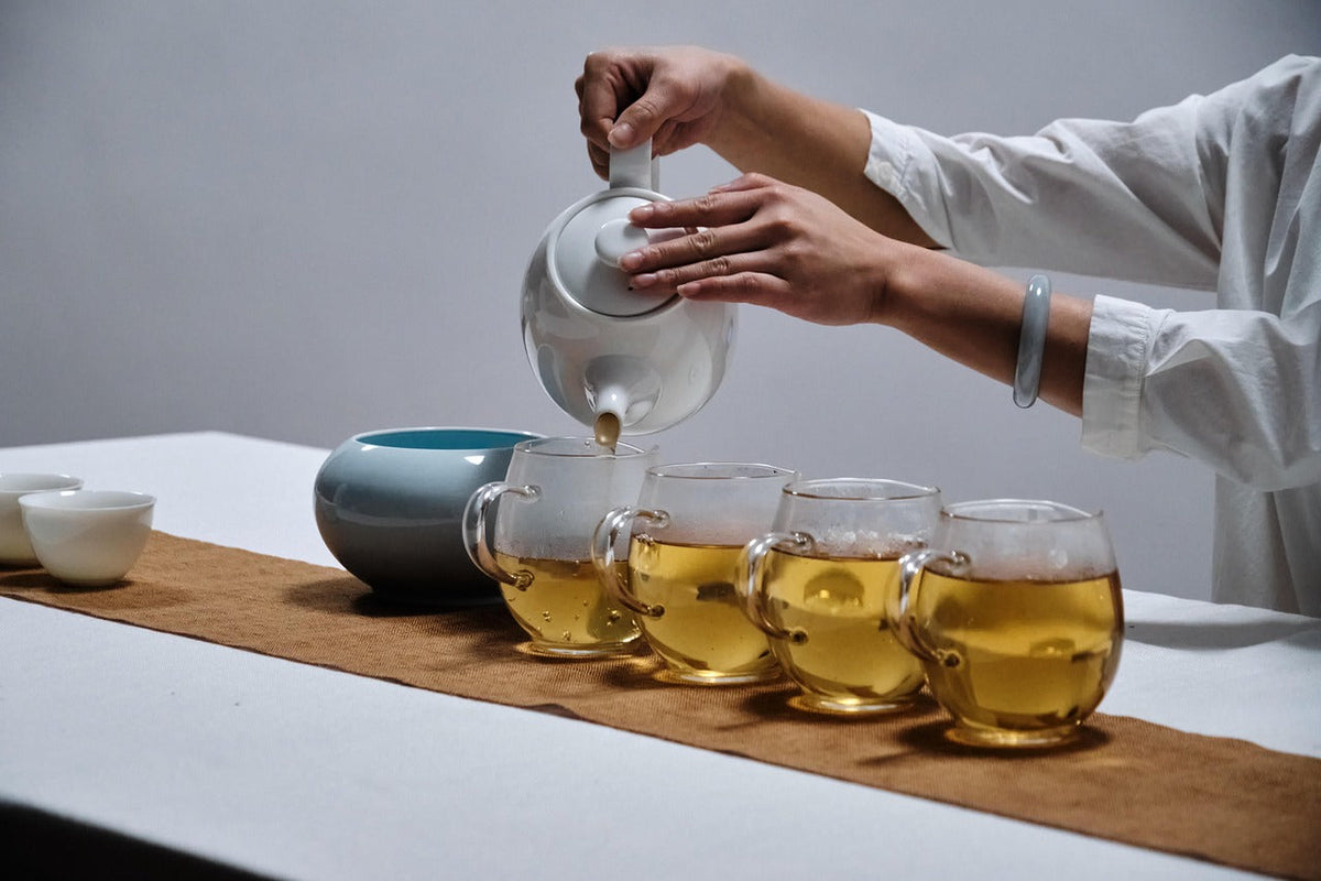 Raw pu'er tea poured into four glass cups for a side-by-side tasting