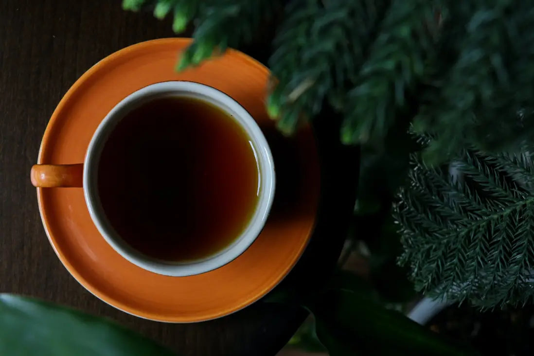 Orange teacup with dark brewed Pu Erh tea showcasing raw versus ripe tea differences