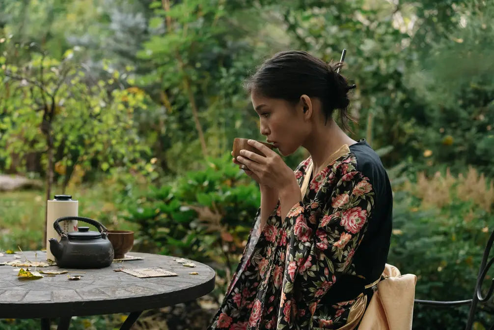 Woman in a floral kimono sipping tea at a garden table