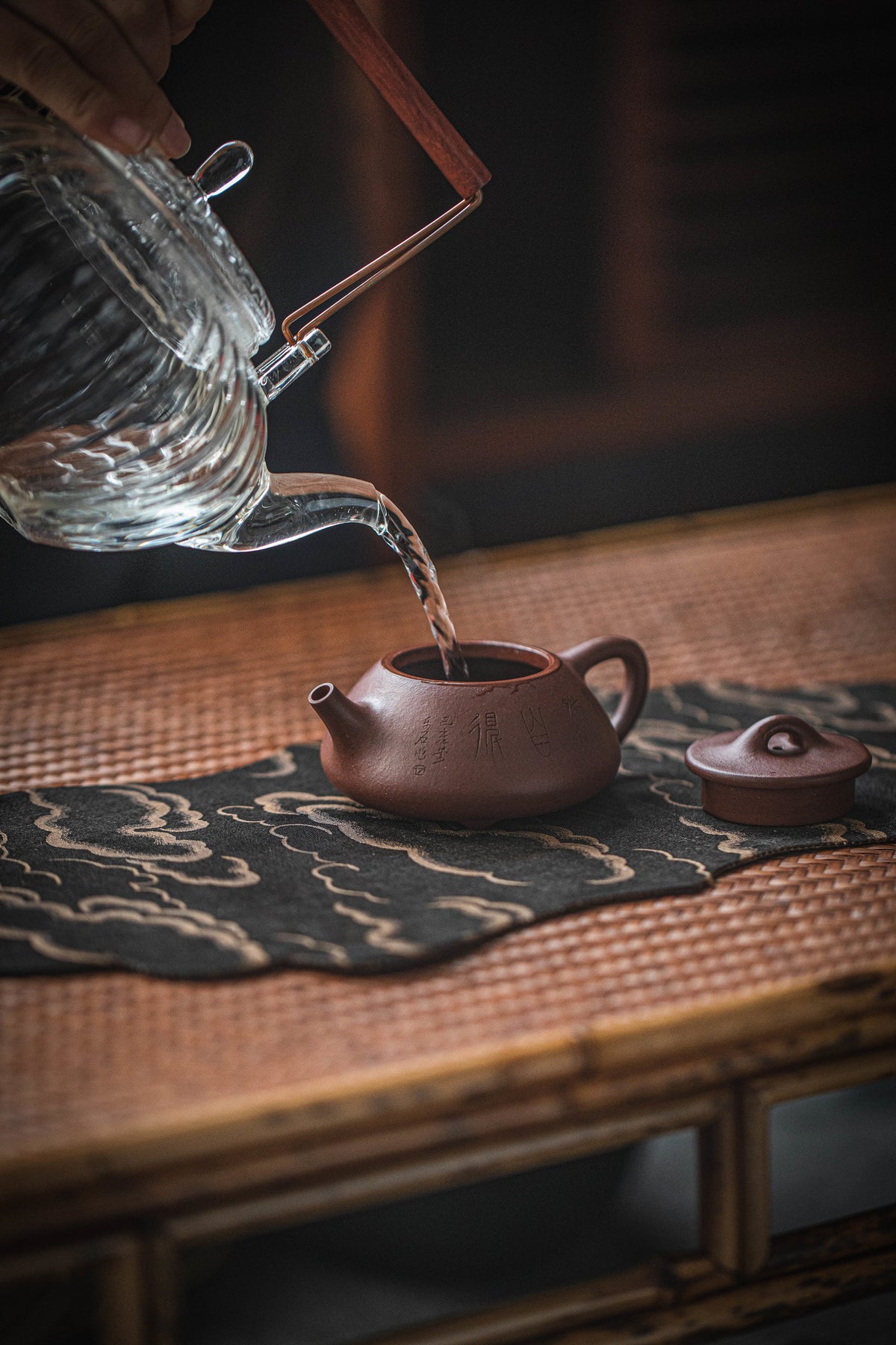 Water poured into a clay teapot on a tea table
