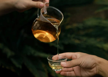 Tea being poured into a glass cup for an article about why tea is poured seven-tenths full