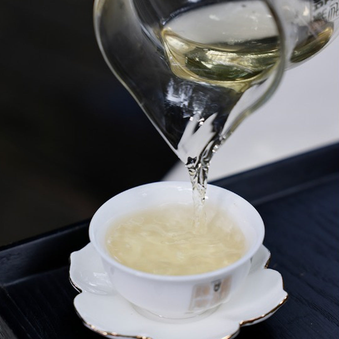 Pouring freshly brewed pu-erh into a white tasting cup