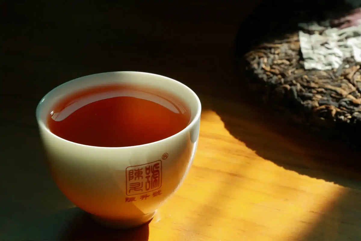 A white ceramic teacup filled with dark amber tea.